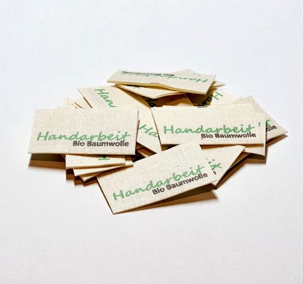 20 St. Textiletiketten aus Naturbaumwollband mit der Aufschrift in grün "Handarbeit"